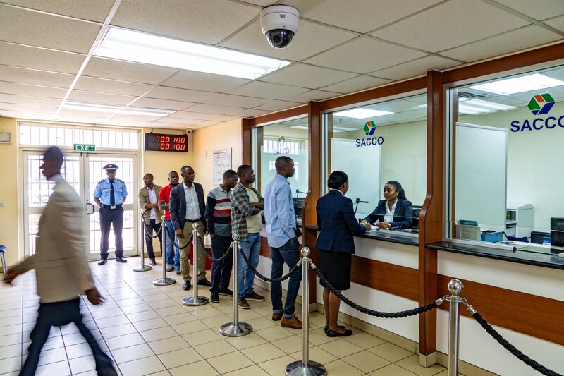 A busy SACCO banking hall with customers queuing at teller counters