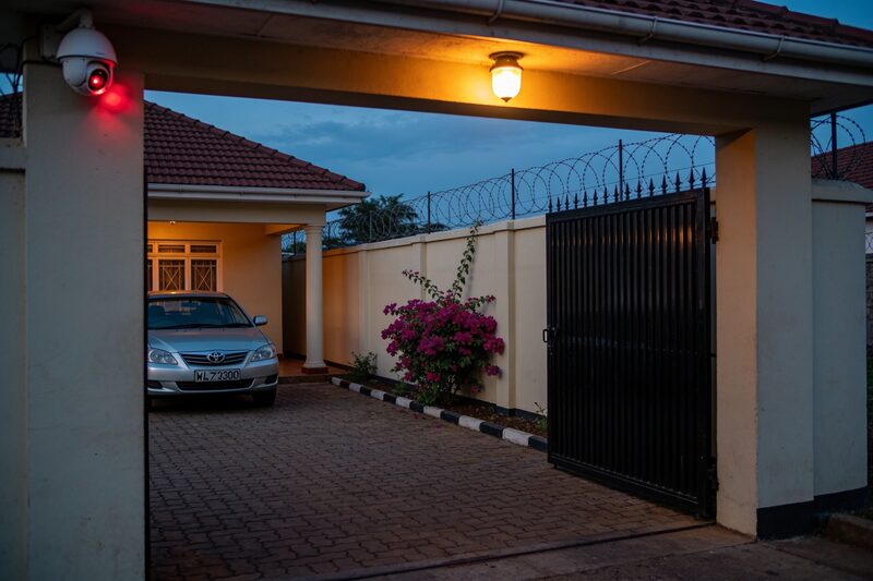A family home compound at dusk with a gate, wall and a dome camera