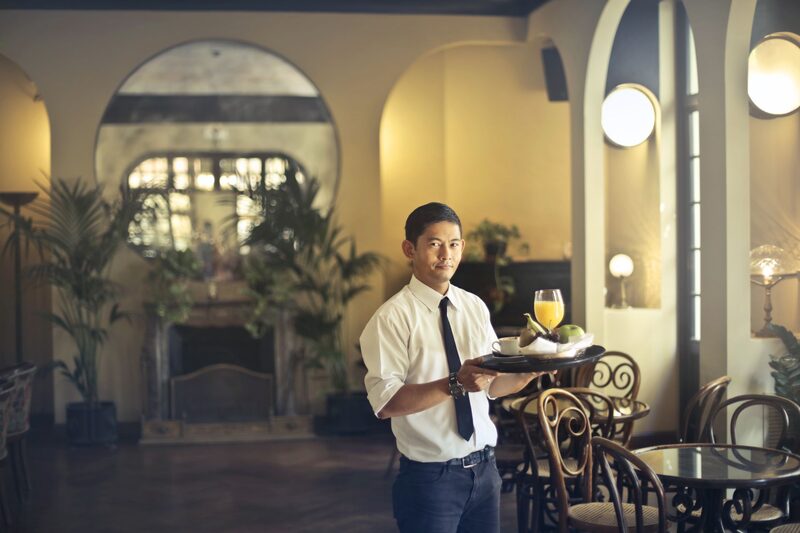 A waiter carrying a tray through a hotel restaurant